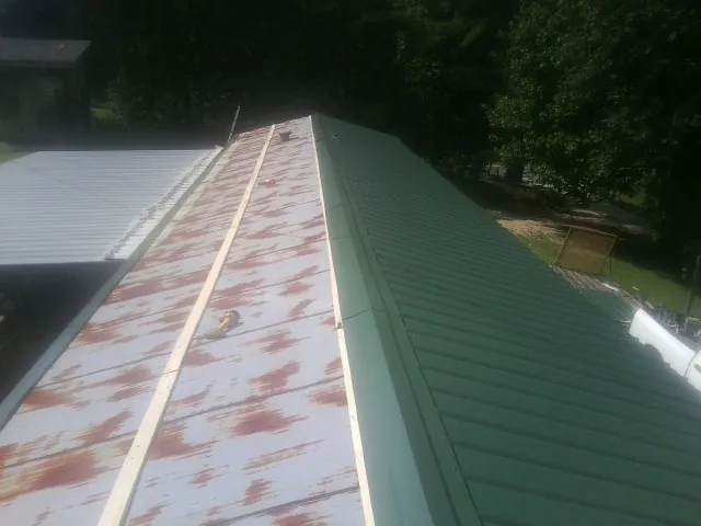 Old rusted panels beside newly installed green metal roofing — Wind Damage Roof Repair by Roofing Brothers in Wabasso
