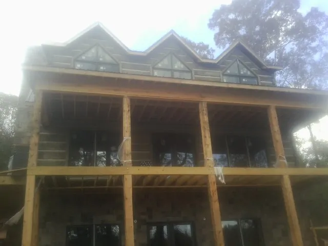 Dormers and porch framing on a large log home under construction — Roof Coating work by our crew in Wabasso